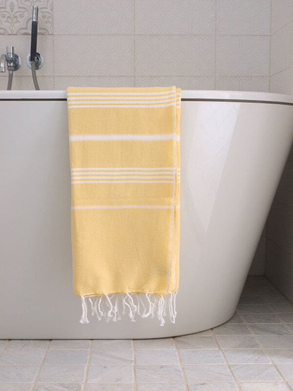 Serviette jaune sur baignoire moderne en céramique.