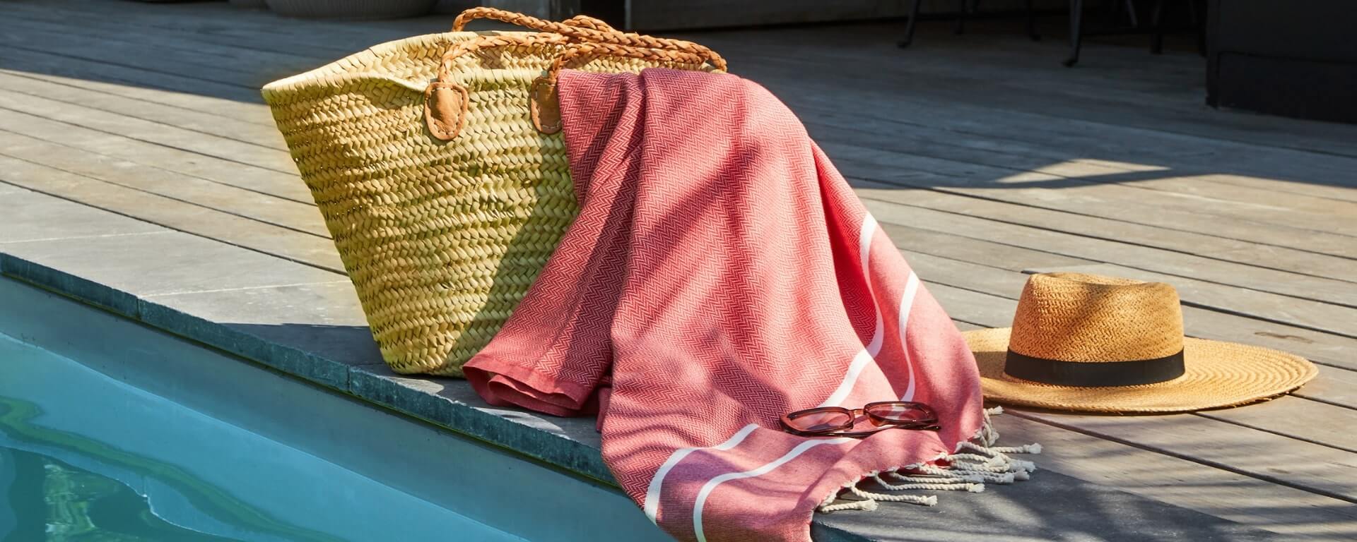 Panier et chapeau de paille au bord de piscine.