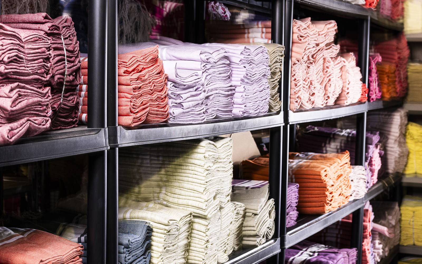 Étagères remplies de serviettes colorées pliées.